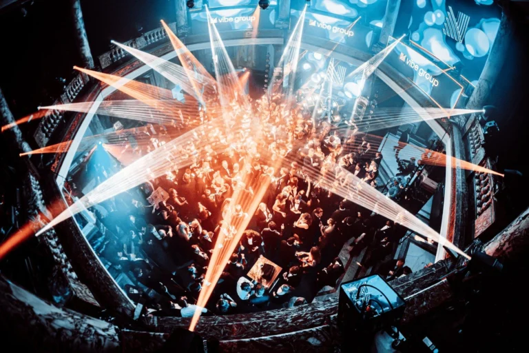 Afbeelding van een vol bedrijfsfeest met spectaculaire lampen in de kleuren blauw en oranje.