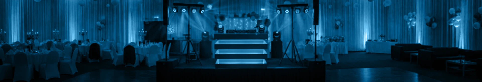 Foto van een feestzaal met midden in de ruimte een podium met DJ booth.